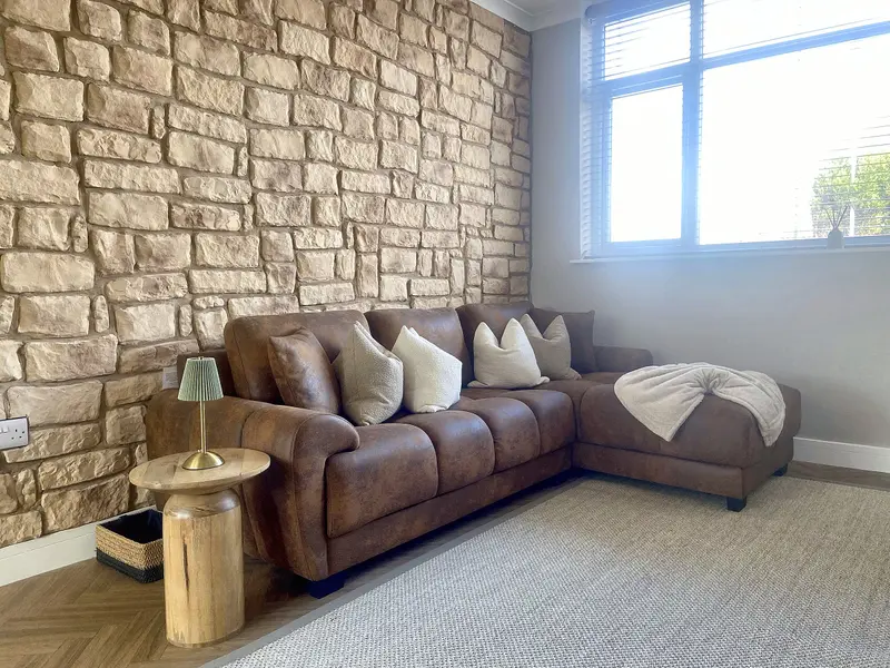 Living room at Edinburgh Road Retreat with corner sofa and feature stone wall