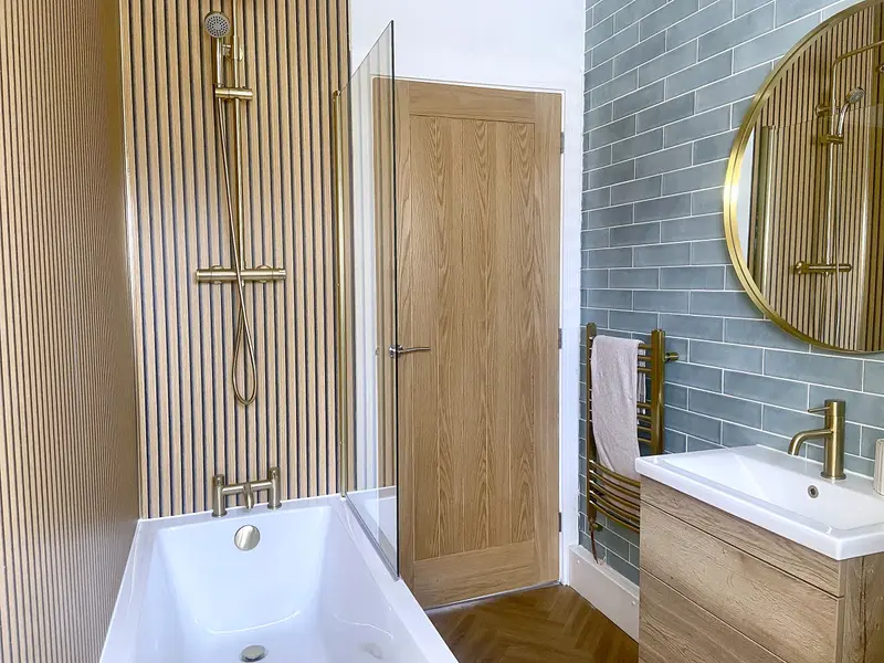Bathroom with brushed-brass rainfall shower over the bath and oak-panelled wall