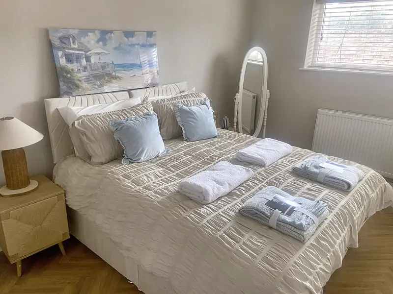 Bedroom with zip-and-link beds made up as a large double, with fresh towels