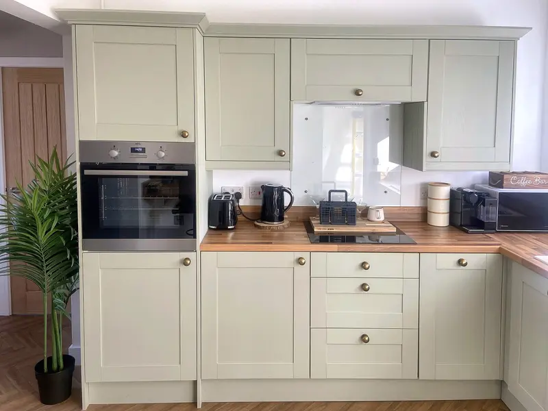 Sage-green Shaker kitchen with AEG oven and brass handles