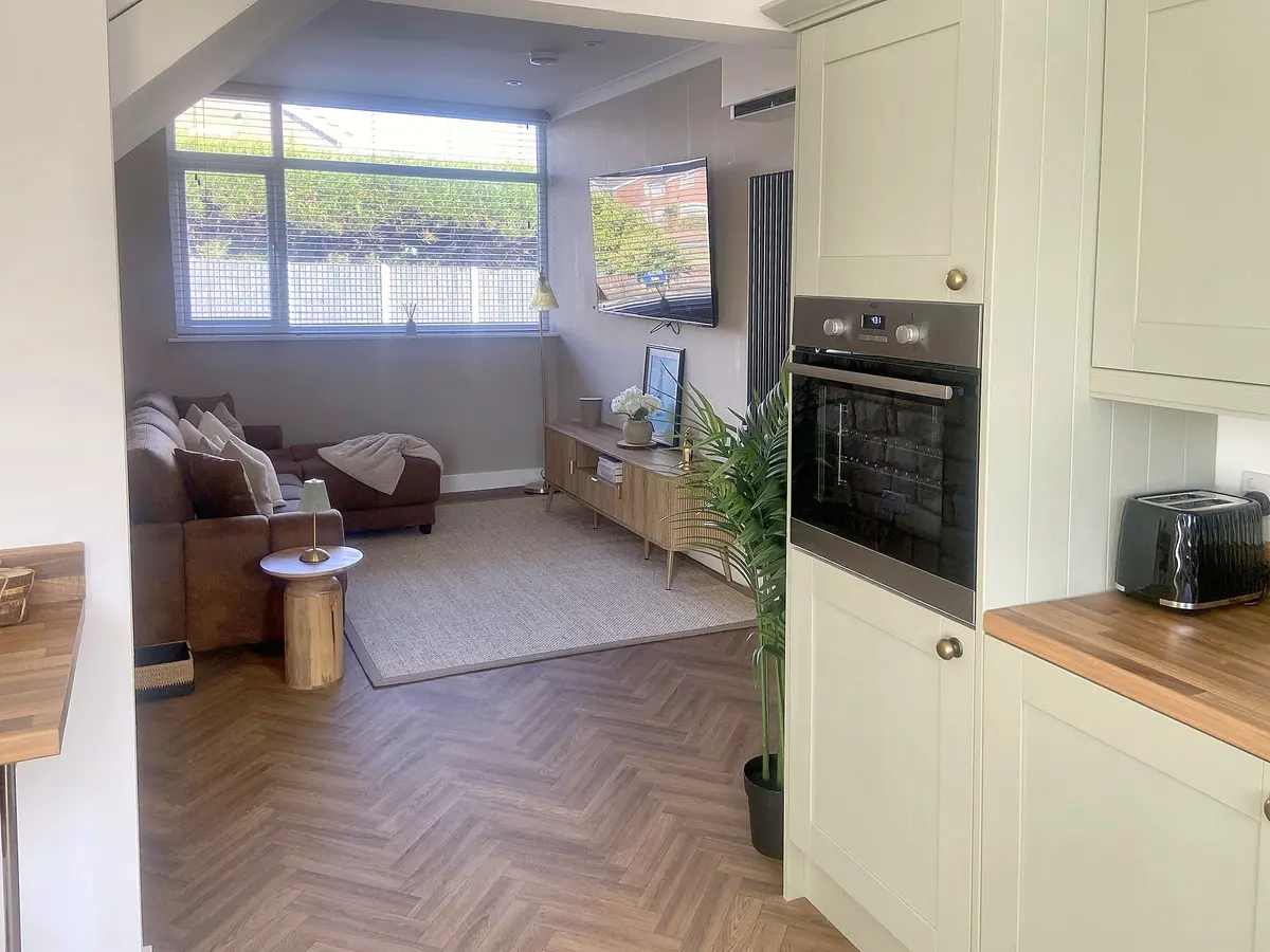 Open-plan view from the sage-green kitchen into the living room at Edinburgh Road Retreat
