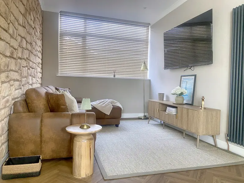 Living room with corner sofa, wall-mounted smart TV and oak sideboard