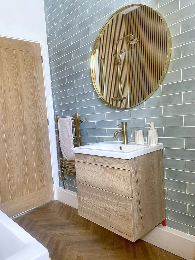 Oak vanity unit with a round brass mirror and blue-grey tiles