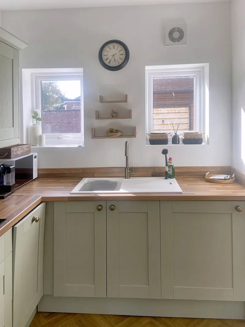 Kitchen sink beneath two windows with open shelving
