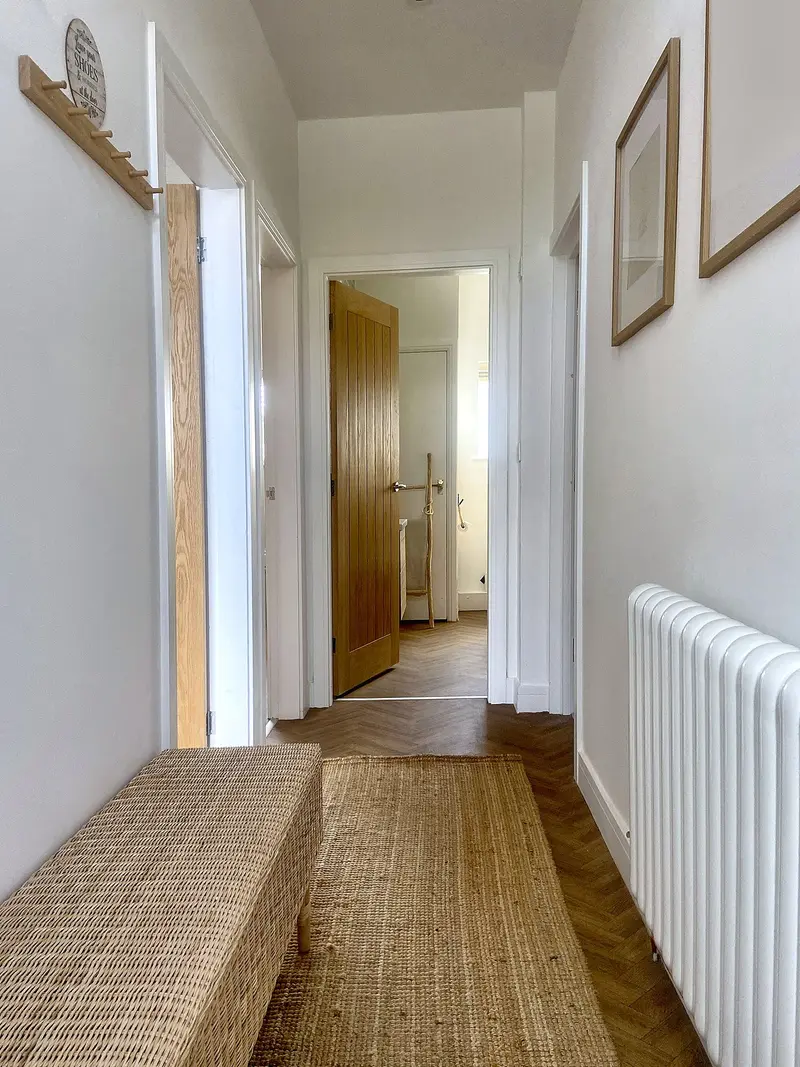 Hallway with radiator and oak doors to the bedrooms and bathroom