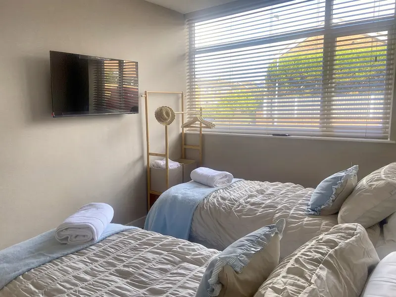 Twin bedroom with smart TV and window blinds